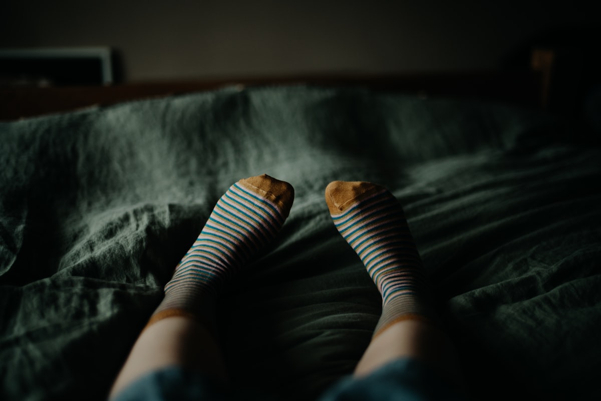 a person with striped socks laying on a bed related to Queen Size Bed Sizes Explained