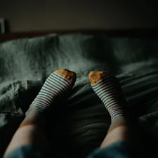 a person with striped socks laying on a bed related to Queen Size Bed Sizes Explained