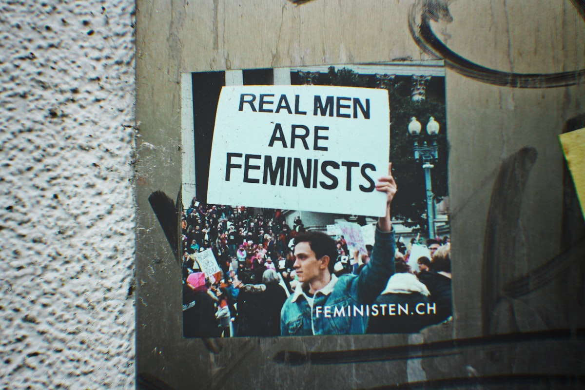 a picture of a man holding a sign that says real men are feminists related to What Men Really Want in Bed, Revealed: Behind the Scenes of Their Mental and Emotional Needs