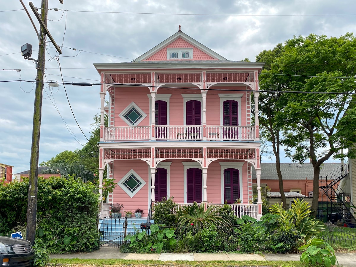 a pink and white house with a car parked in front of it related to Discover the Charm of New Orleans: A Guide to Bed and Breakfasts