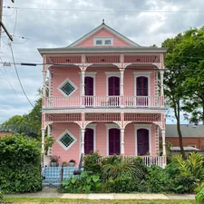 a pink and white house with a car parked in front of it related to Discover the Charm of New Orleans: A Guide to Bed and Breakfasts