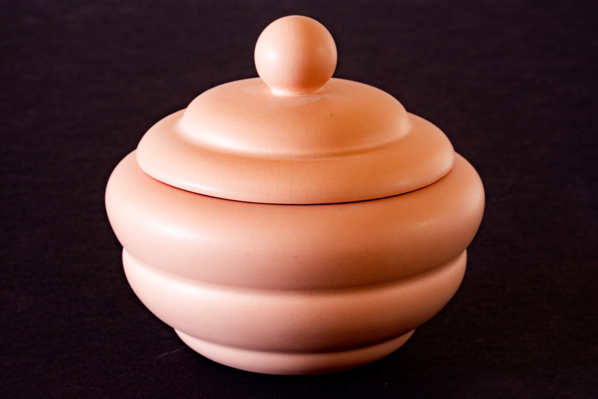 a pink ceramic container sitting on a black surface related to Small Clay Chiminea: A Perfect Blend of Warmth and Elegance