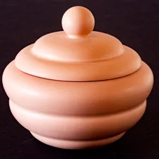 a pink ceramic container sitting on a black surface related to Small Clay Chiminea: A Perfect Blend of Warmth and Elegance