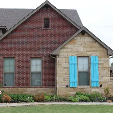 a red brick house with blue shutters related to Cozy Oklahoma Getaways