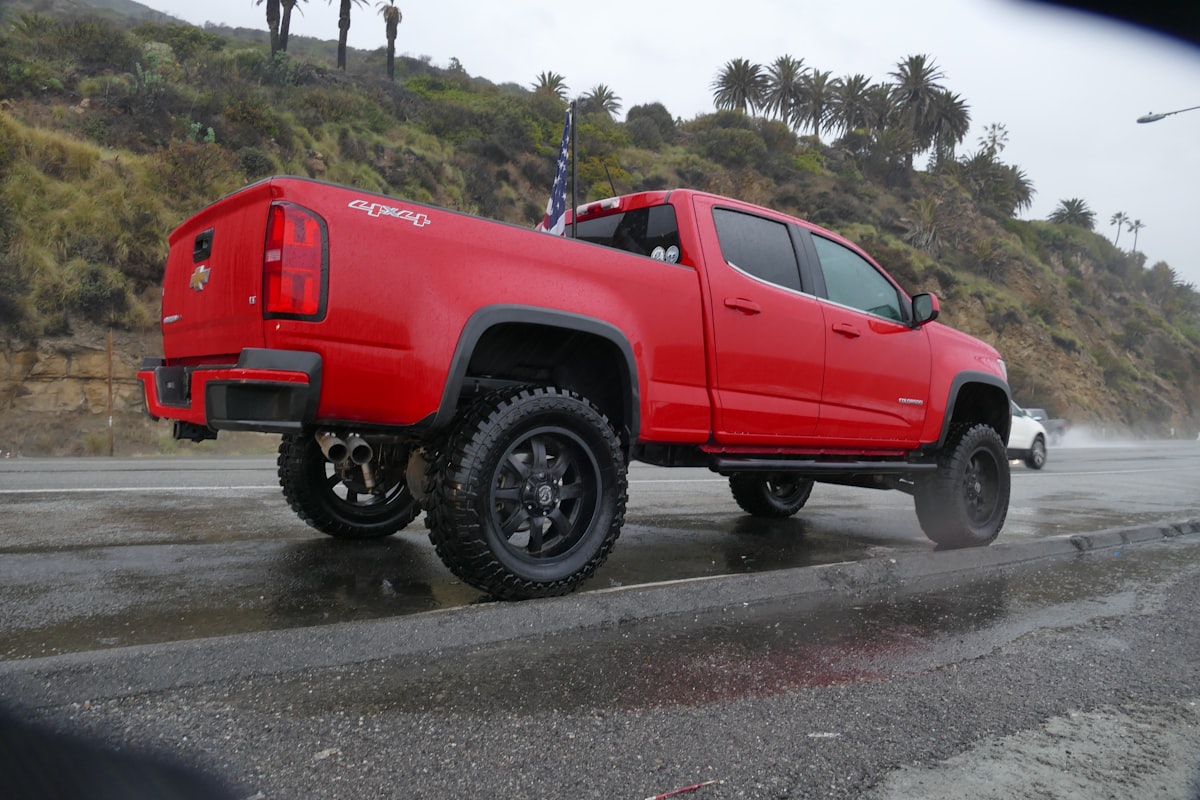 A red truck is driving on a wet road related to Understanding Chevy Avalanche Bed Sizes: A Complete Guide