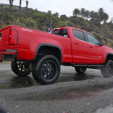 A red truck is driving on a wet road related to Understanding Chevy Avalanche Bed Sizes: A Complete Guide