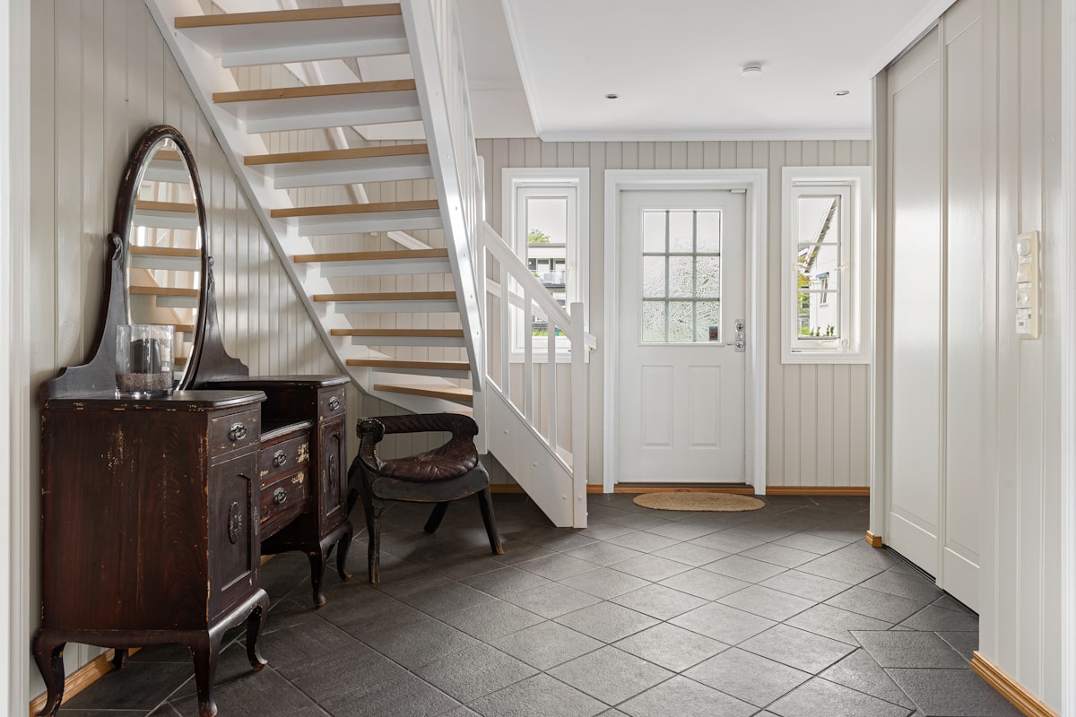 A room with a staircase and a table with a mirror related to Transform Your Entryway with the Perfect Floor Tile