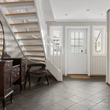 A room with a staircase and a table with a mirror related to Transform Your Entryway with the Perfect Floor Tile
