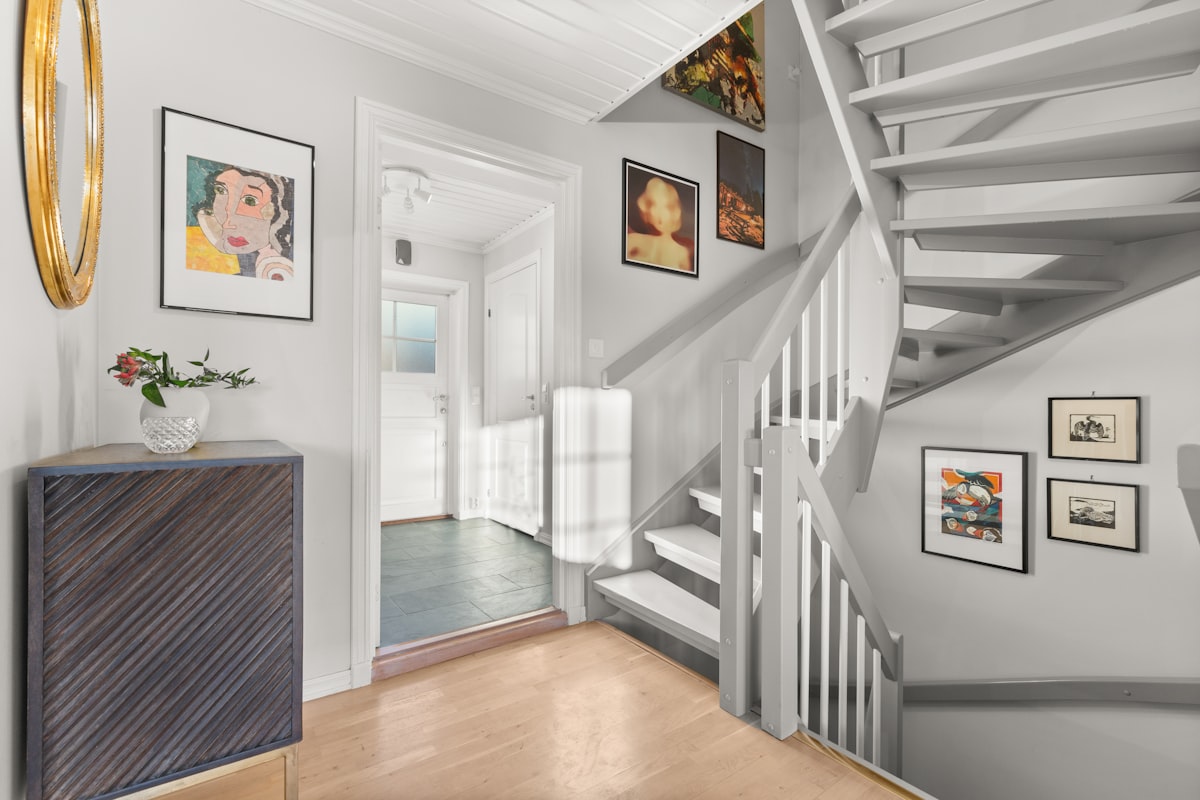 A room with a staircase and pictures on the wall related to The Art of Entryway Essentials