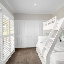 A room with bunk beds and white shutters related to Maximizing Space with Style: The Ultimate Guide to Triple Bunk Beds
