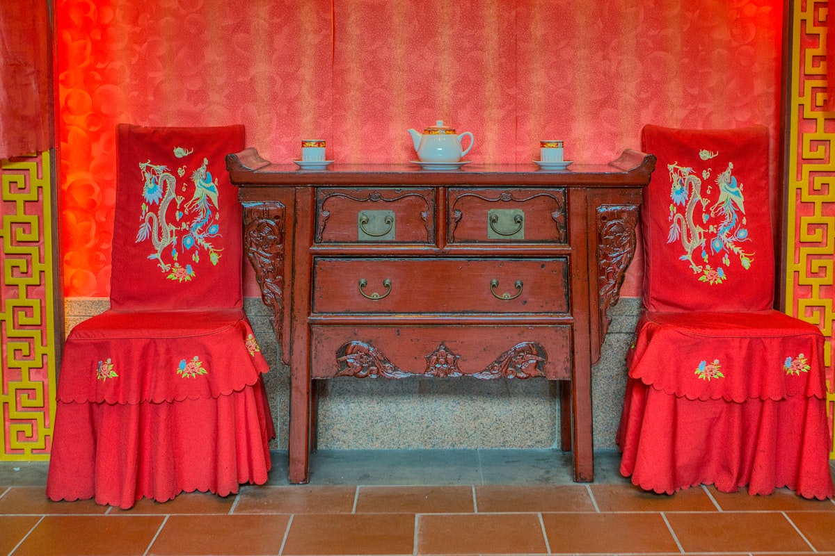 A room with two chairs and a table with a vase on it related to Unveiling the Elegance of Antique Chinese Sideboards