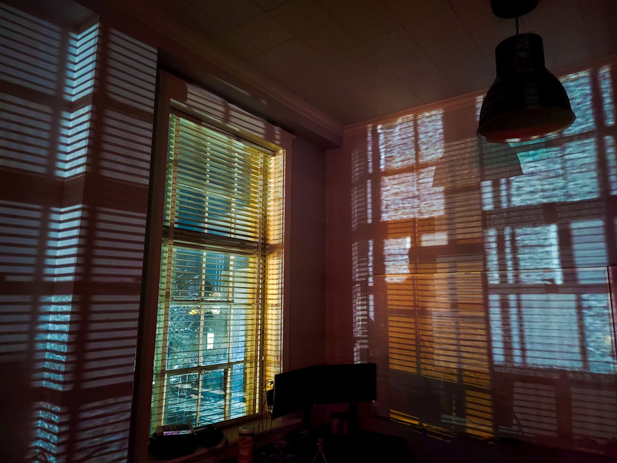 a room with two windows that have blinds on them related to Window Treatments 101: Mastering Curtains, Swags, and Valances