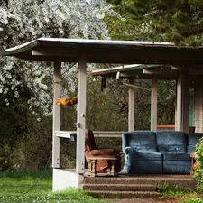 A rustic porch with a couch and chair. related to Warm Up Your Outdoor Space with a Chiminea: Where to Find the Perfect One