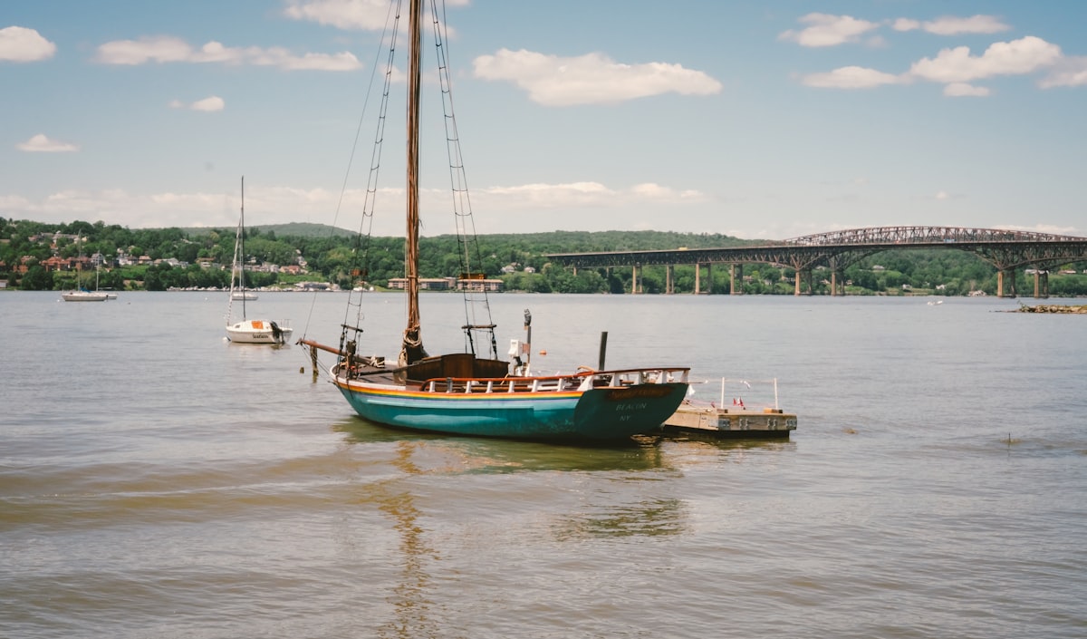 A sailboat moored near a dock with a distant bridge related to Charming Bed and Breakfasts in Beacon, NY: A Perfect Escape