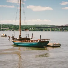A sailboat moored near a dock with a distant bridge related to Charming Bed and Breakfasts in Beacon, NY: A Perfect Escape