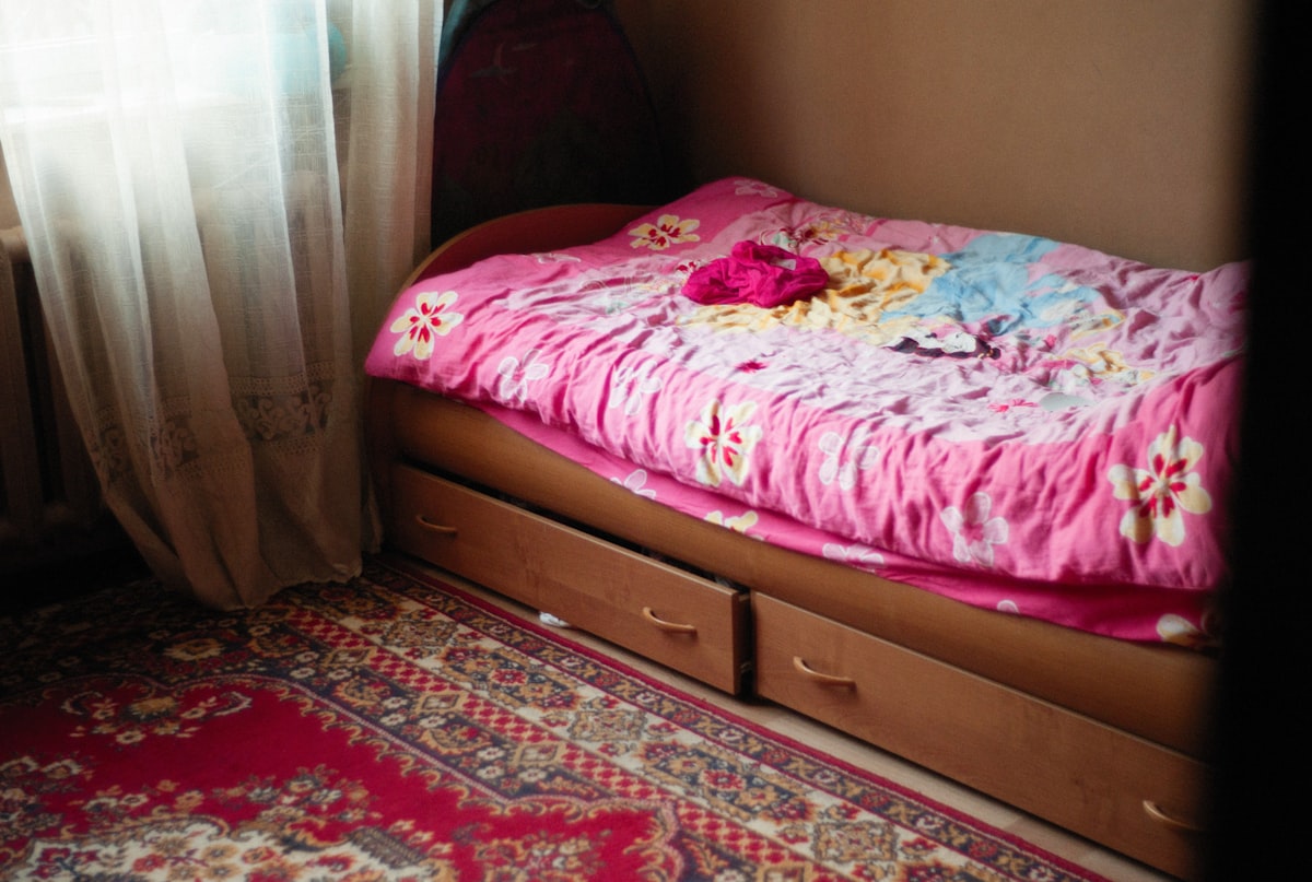 a small bed with a pink blanket on top of it related to Beyond the Basics:  Transforming Kids' Bedrooms with Extraordinary Beds