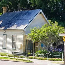 A small white house sitting on the side of a road related to Blossoming Corner Oasis