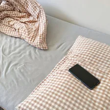 A smartphone rests on a checkered pillow on a bed. related to Single Bed Coverlets