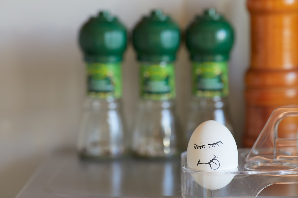 A smiling face with eyes, mouth, and tongue hanging out is drawn on a chicken egg. Emotional egg in the background of the kitchen related to Big Green Egg Chiminea Price