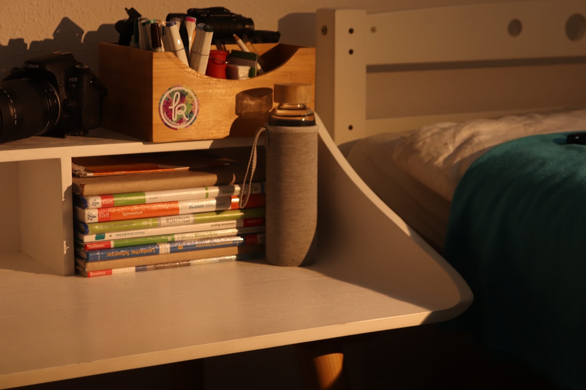 a stack of books sitting on top of a white desk related to Maximizing Space: Kids Beds with Built-in Storage Solutions