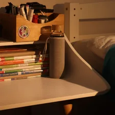 a stack of books sitting on top of a white desk related to Maximizing Space: Kids Beds with Built-in Storage Solutions