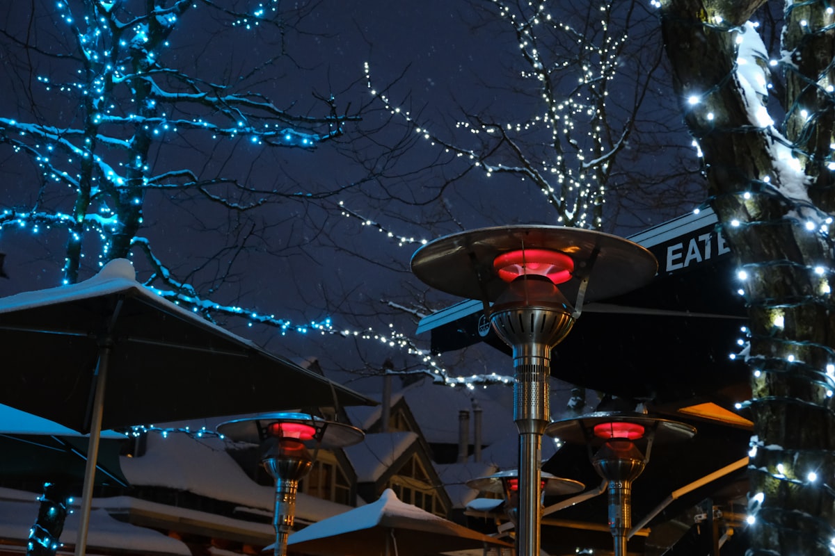 a street light with lights on it next to a tree related to The Art of Outdoor Heating: Cast Aluminum Chimineas