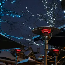a street light with lights on it next to a tree related to The Art of Outdoor Heating: Cast Aluminum Chimineas