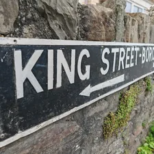 a street sign mounted to a stone wall related to King Coverlets On Sale