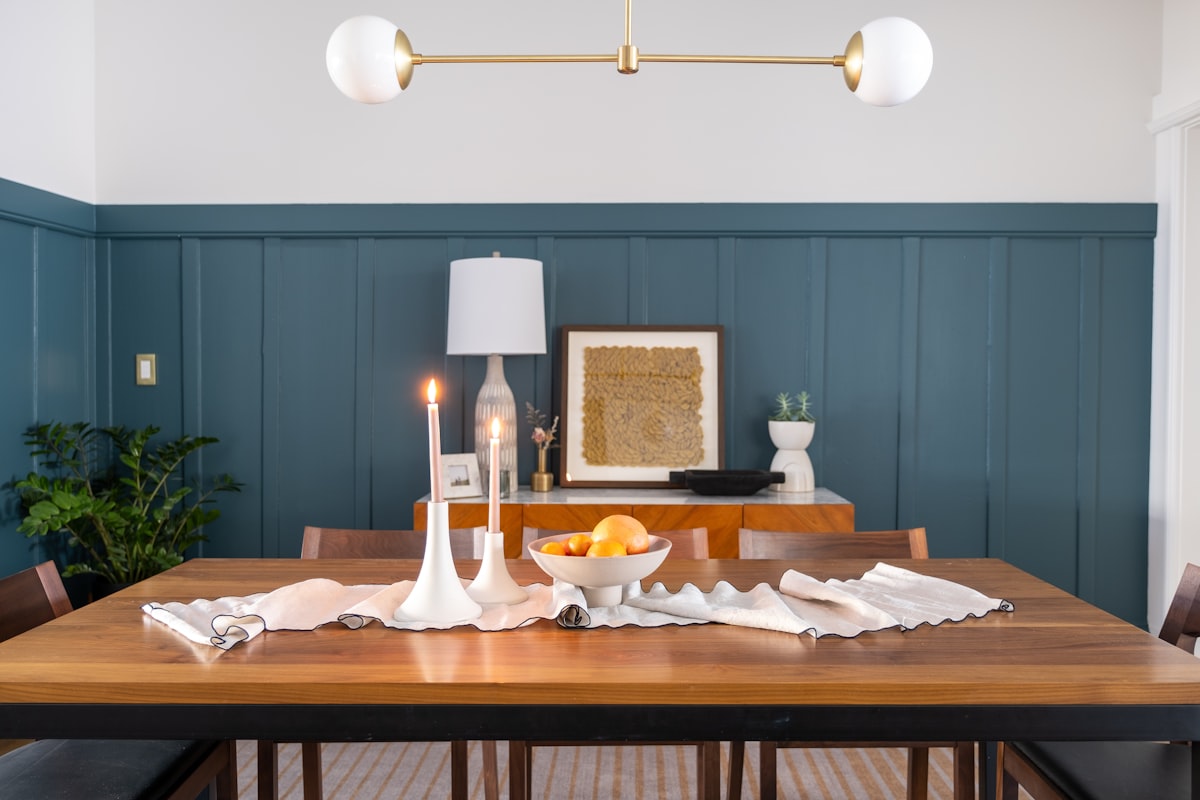 A stylish dining room featuring a table draped with a richly white table cover, complemented by a sleek candle stand casting a warm glow. related to Elevate Your Dining Room with the Perfect Curtains and Valances