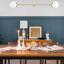 A stylish dining room featuring a table draped with a richly white table cover, complemented by a sleek candle stand casting a warm glow. related to Elevate Your Dining Room with the Perfect Curtains and Valances