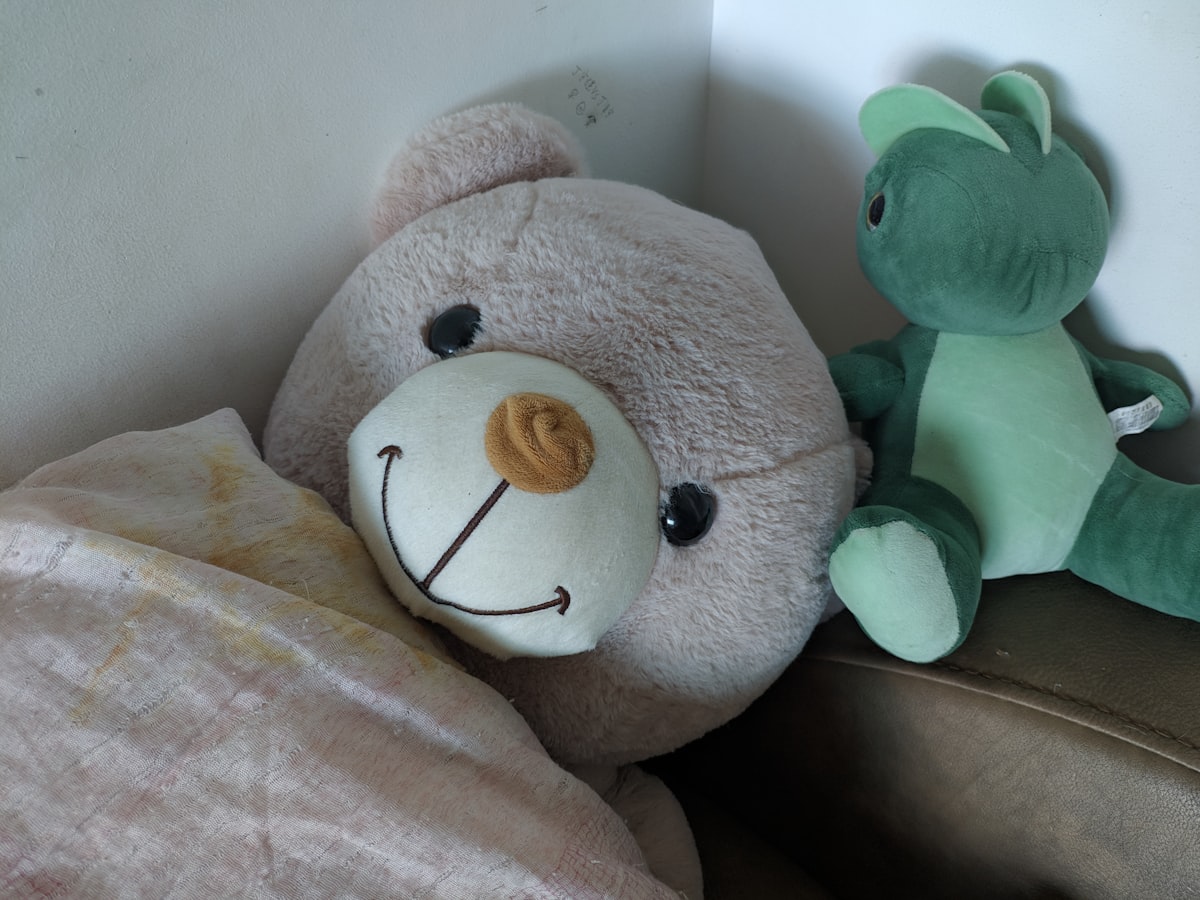 a teddy bear sitting next to a stuffed frog related to How to Build the Perfect Bear Bed for Your Furry Friend
