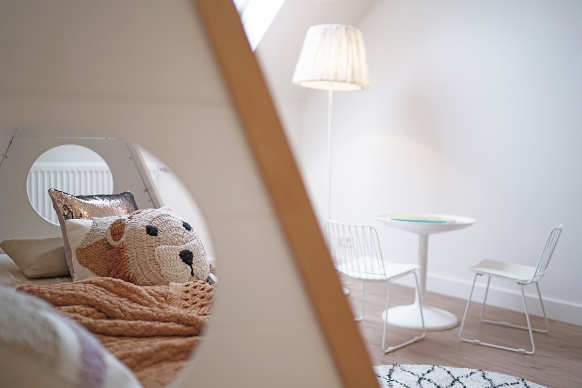 a teddy bear sitting on a bed in a room related to Beyond the Basics:  Transforming Kids' Bedrooms with Extraordinary Beds
