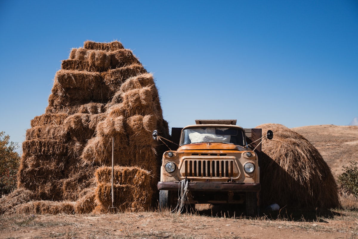 a truck is parked next to a pile of hay related to Bale Bed Trucks for Sale: Find the Perfect Vehicle for Your Farming Needs