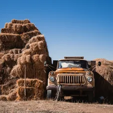 a truck is parked next to a pile of hay related to Bale Bed Trucks for Sale: Find the Perfect Vehicle for Your Farming Needs
