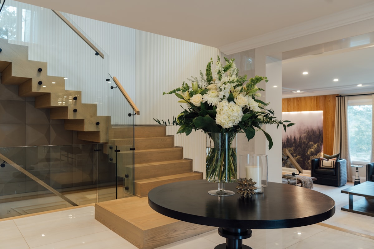 a vase of flowers sitting on top of a table related to Sculptural Elegance: Glass Entryway Tables for Modern Homes