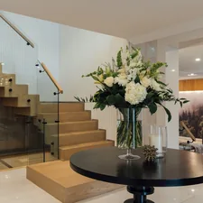 a vase of flowers sitting on top of a table related to Sculptural Elegance: Glass Entryway Tables for Modern Homes