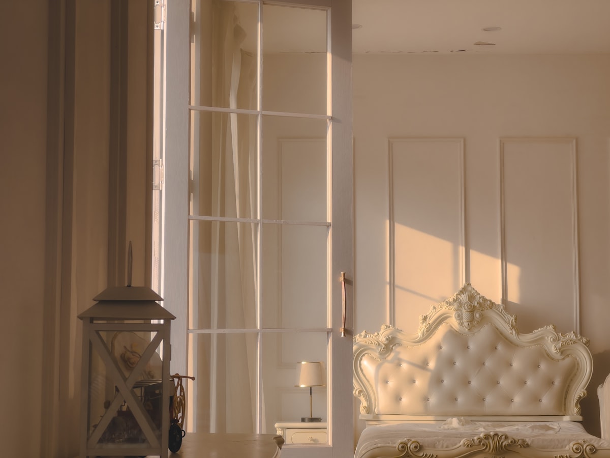 a white bed sitting next to a window in a bedroom related to Sliding Door Valances: Elegant Solutions for Your Space