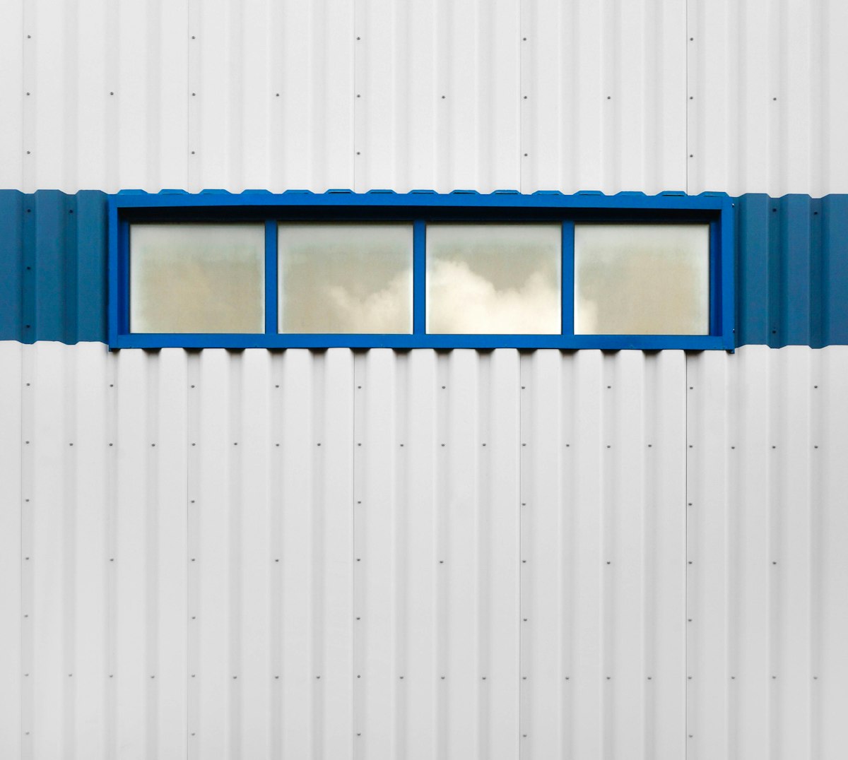 a white building with a blue window on the side of it related to Straight Window Valances