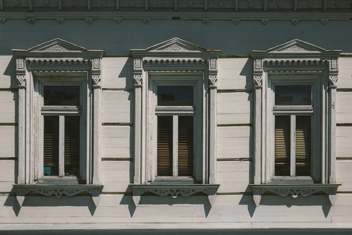 a white building with three windows and a street sign in front of it related to Traditional Window Valances