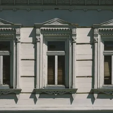 a white building with three windows and a street sign in front of it related to Traditional Window Valances