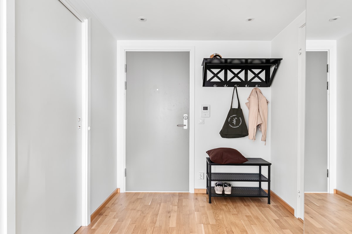A white hallway with a bench and coat rack related to Metal Entryway Bench with Coat Rack: A Perfect Combo for Your Home's Entrance
