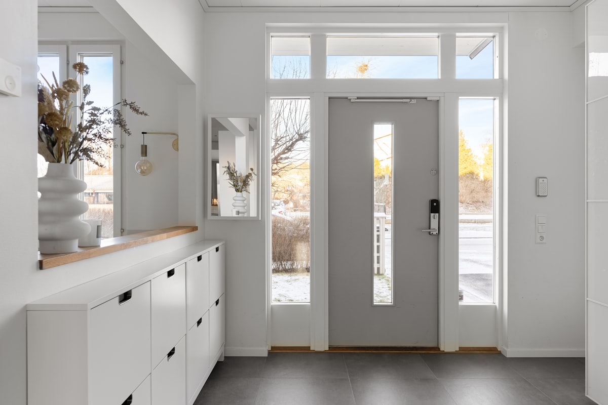 A white hallway with a gray door and white cabinets related to Maximizing Entryway Style with Elegance