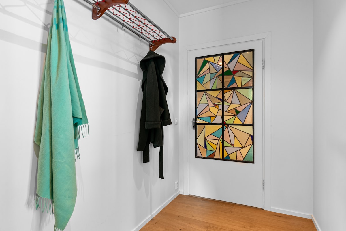 A white room with a coat rack and a painting on the wall related to The Art of Entryway Essentials