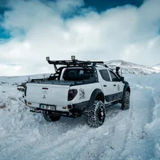 a white truck driving through a snow covered field related to Find the Best Truck Bed Covers Near Me: Top Options and Reviews