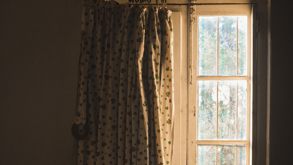 a window with curtains and a cat sitting on the window sill related to Elevate Your Windows with Curtains, Valances, and Swags