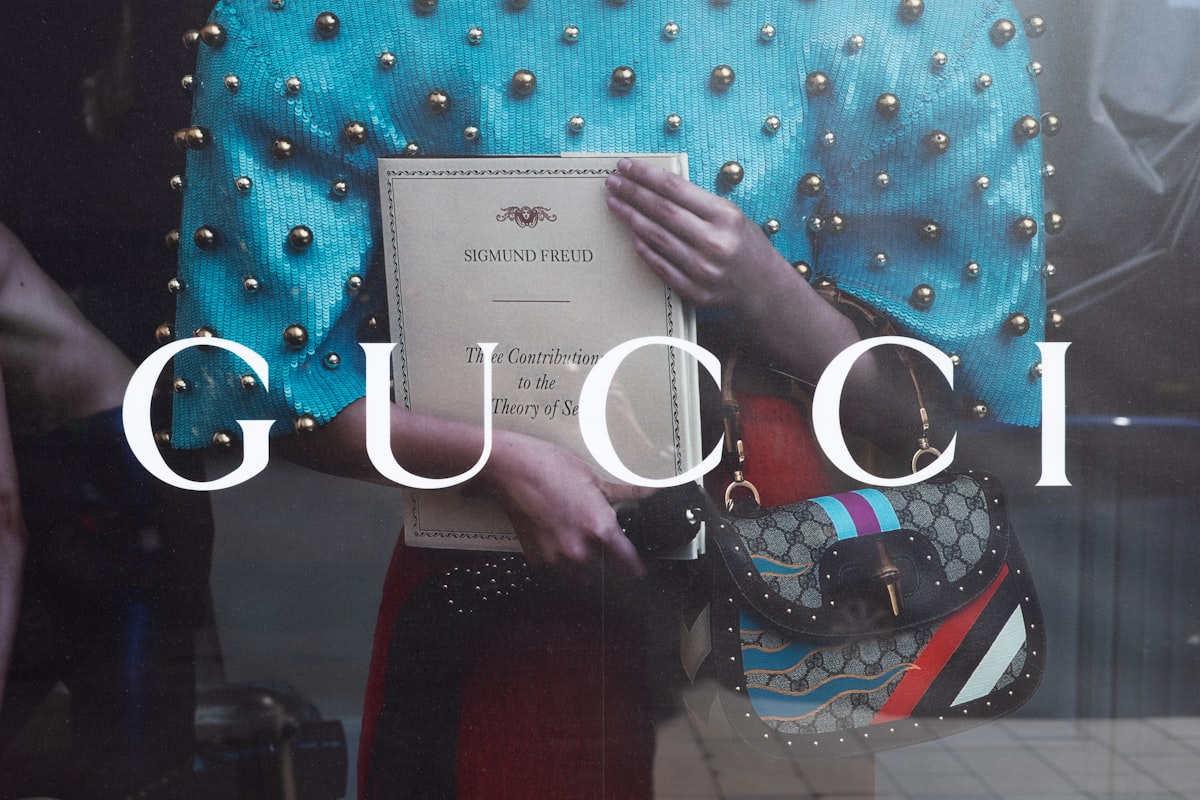 a woman holding a gucci bag in front of a window related to Luxury Redefined: The Elegance of Gucci Bedding Sets for a Stylish Bedroom