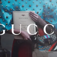 a woman holding a gucci bag in front of a window related to Luxury Redefined: The Elegance of Gucci Bedding Sets for a Stylish Bedroom