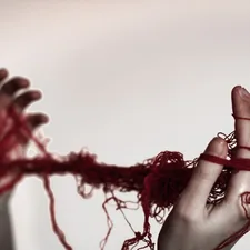 A woman holding a red string in her hands related to Snuggle Up in Style: Unraveling the Mystery of Duvet Coverlets