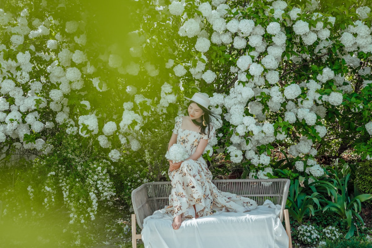 A woman in a dress poses among blossoms. related to Blossoming Style: The Ultimate Guide to Floral Crib Bedding