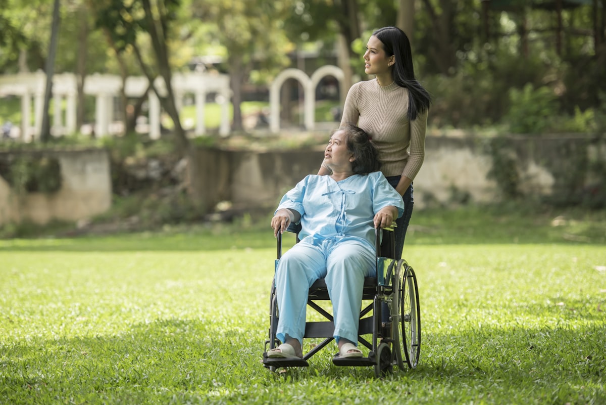 A woman in a wheelchair standing next to a man in a park related to Elevating Care: The Comfort and Convenience of Invacare Hospital Beds